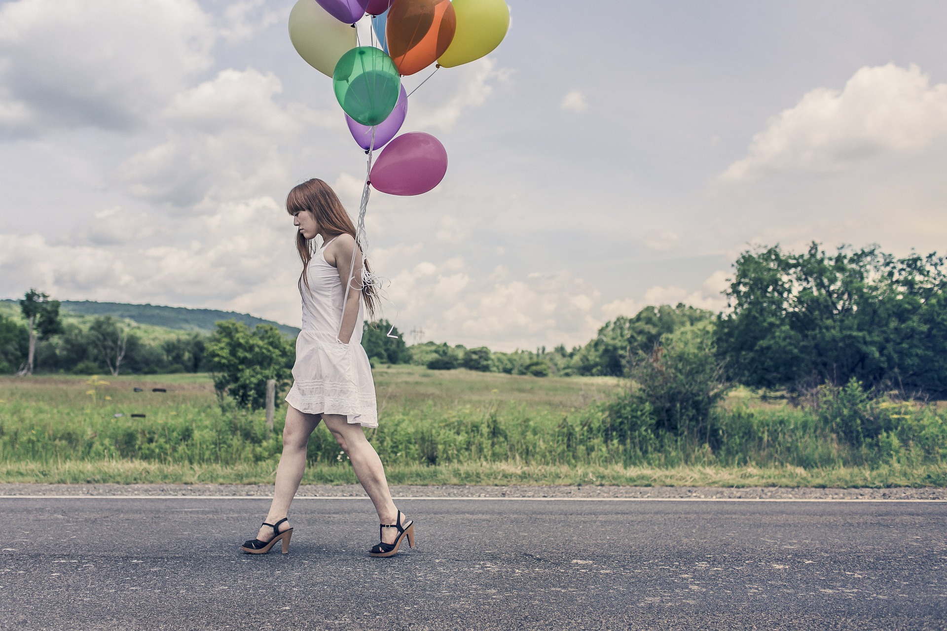 balloons-388973_1920 Frau im weißen Kleid auf einer Straße mit bunten Luftballons in der Hand