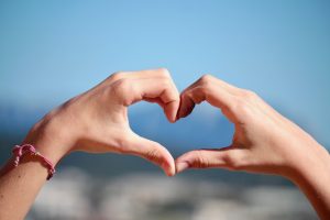 Zwei Hände formen ein Herz vor blauem Himmel als Sinnbild für Herzintelligenz