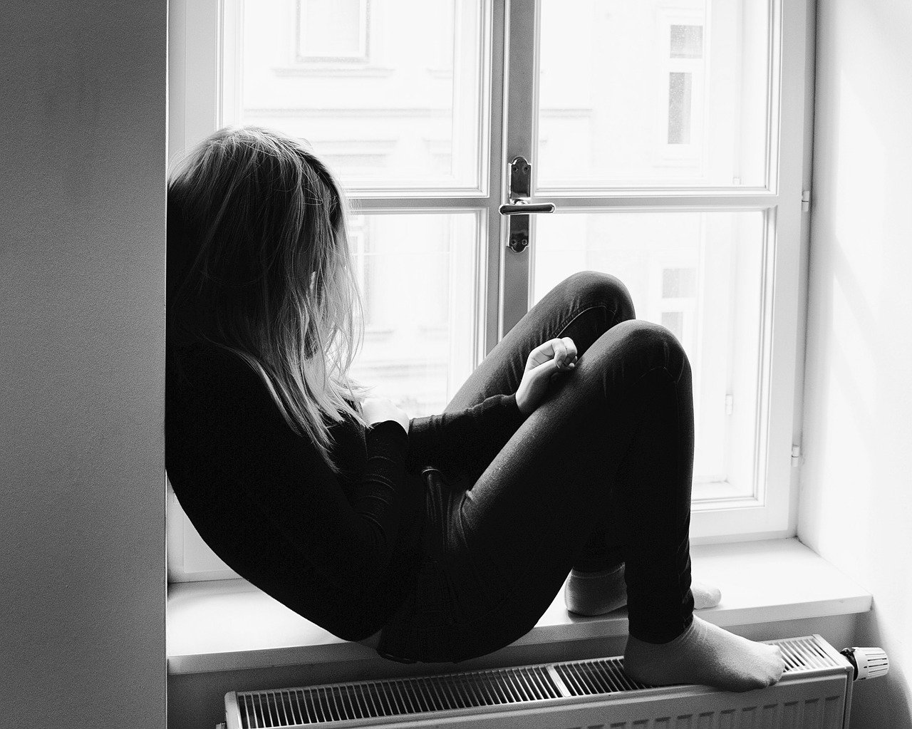 desperate-2100307_1280 Frau sitzt zusammengesunken im Fenster als Sinnbild für den Schmerz von Trauma