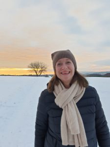 Frau in einer Schneelandschaft mit Baum im Hintergrund als Zeichen von Verbundenheit