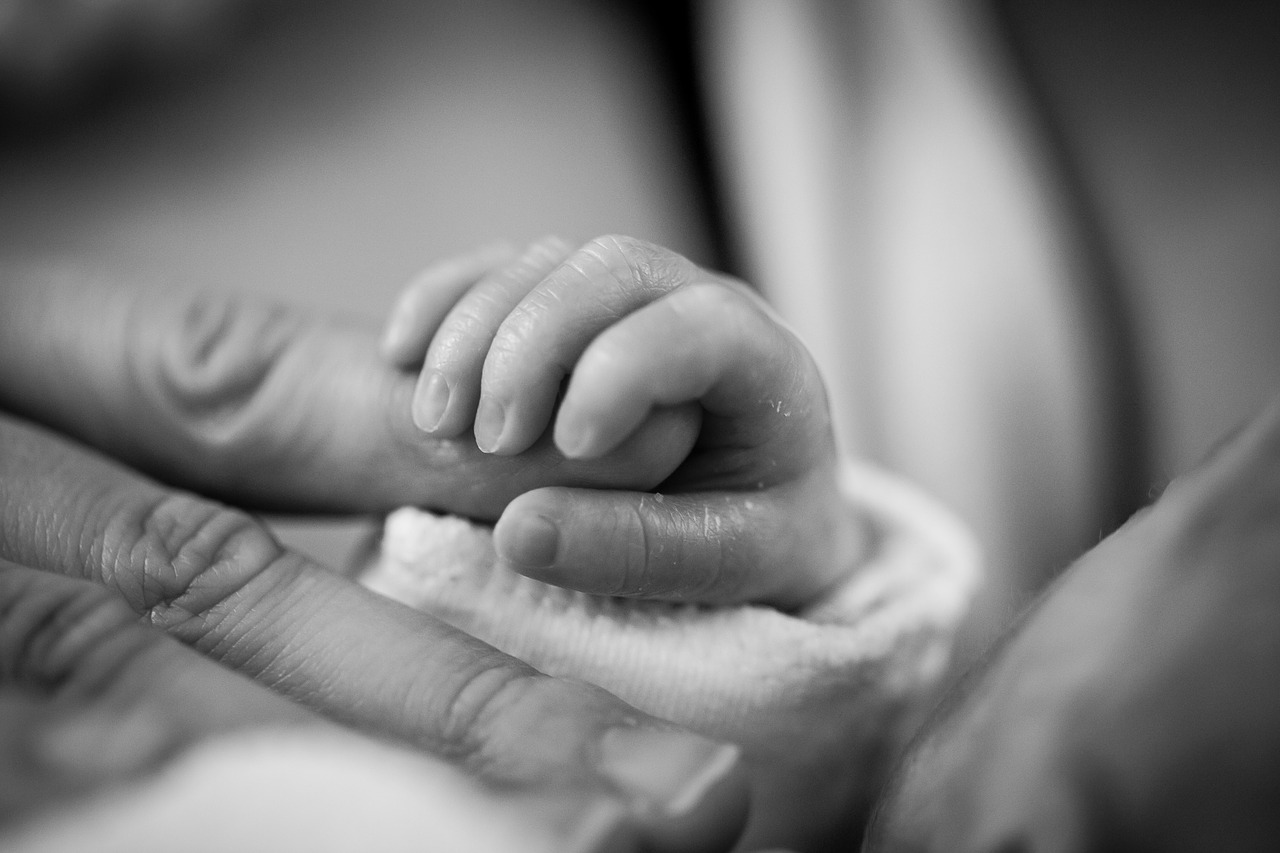 Babyhand die einen Finger hält als Symbol für das innere kInd