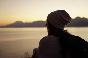 Frau im Profil mit Mütze in der Abenddämmerung als Sinnbild für das Gefühl der Verbundenheit und des All-ein-seins